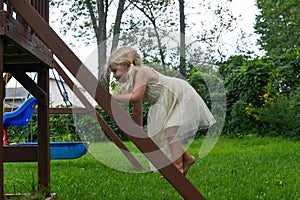 Little girl climbing swingset ladder in a dress photo