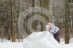 Little girl climbing top of snowy hill in