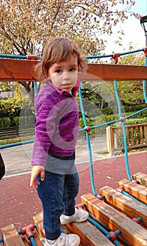 Little girl climbing on a wood bridge.