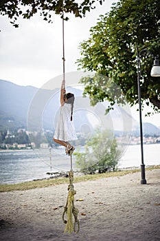 Little girl climbs on a big rope in the outdoor