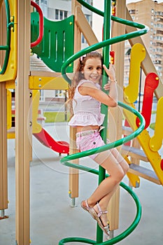 Little girl climbs a pole at children playground