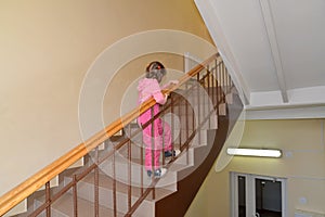 The little girl climbs up on a ladder handrail the second floor