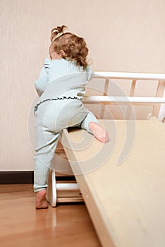 A little girl climbs a wooden slide in the gym. The child goes in for sports and develops