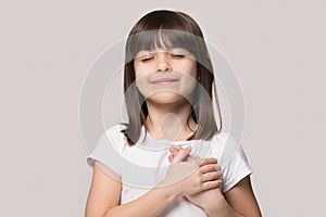 Little girl closed eyes hold hand on chest feels gratitude photo