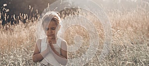 Little girl closed her eyes praying at sunset. Hands folded in prayer concept for faith, spirituality and religion. Hope, concept.