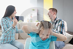 Little girl closing her ears against background of swearing parents at home
