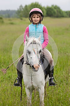 Little girl in the clothes for riding a horse sitting Sharpness on a horse Outdoors