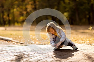 Little girl in coat in autumn plays with toy car on remote control in Park