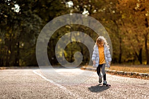 Little girl in coat in autumn plays with toy car on remote control in Park