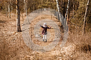 Little girl in a coat runs along a forest path