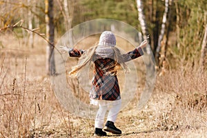 Little girl in a coat runs along a forest path