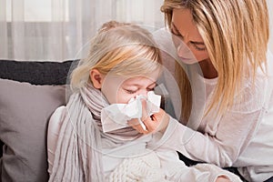 Little girl with cold and blowing her nose