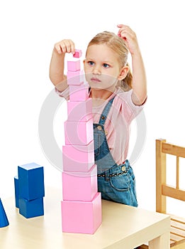 Little girl collects the pink pyramid