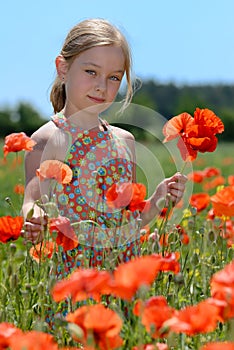 Little girl in a colorful dress on green field