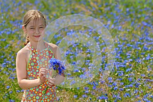 Little girl in a colorful dress on green field