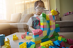 Little girl in a colorful shirt playing with construction toy blocks building a tower