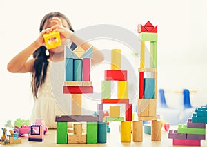 little girl in a colorful shirt playing with construction toy blocks building a tower . Kids playing. Children at day care. Child