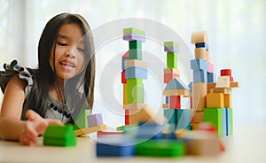 Little girl in a colorful shirt playing with construction toy blocks building a tower . Kids playing. Children at day care. Child