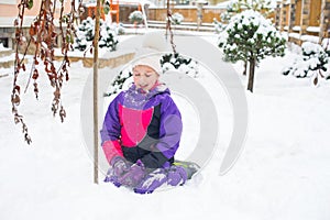 Little girl in colorful suit play in snow in back yard in cold