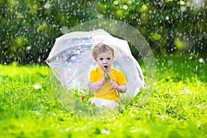 Little girl with colorful umbrella playing in the rain