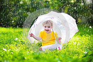 Little girl with colorful umbrella playing in the rain