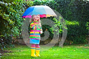 Little girl with colorful umbrella playing in the rain.