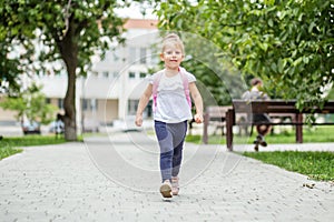 A little girl comes with a backpack for lessons. The concept of school, study, education, friendship, childhood.