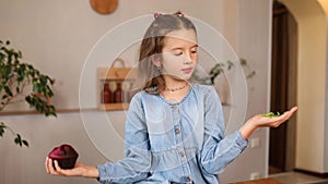 Little girl comparing food, choosing microgreen against sweet cake, Healthy dieting habit