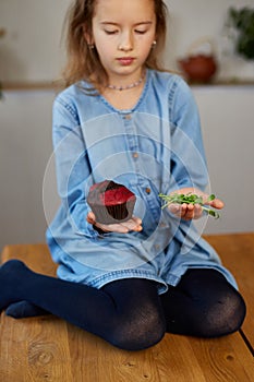 Little girl comparing food, choosing microgreen against sweet cake, Healthy dieting habit