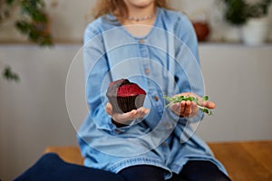 Little girl comparing food, choosing microgreen against sweet cake, Healthy dieting habit