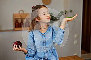 Little girl comparing food, choosing microgreen against sweet cake, Healthy dieting habit