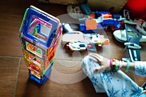 Little girl completing a tower with magnetic pieces inside her room