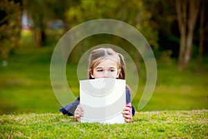 A little girl comtemplating her reading outside.