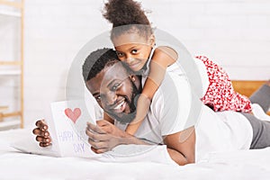 Little girl congratulating her daddy with Father`s Day with greeting card