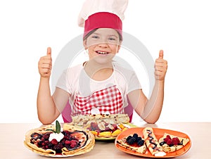 Little girl cook with crepes and thumbs up