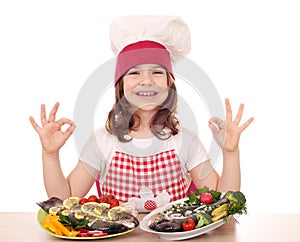 Little girl cook with fishes and ok hand sign