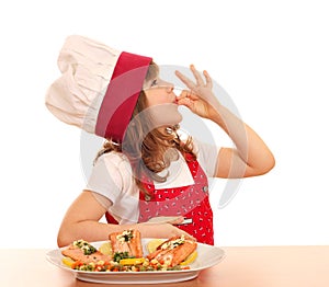 Little girl cook with ok sign and salmon on dish