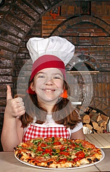 Little girl cook with pizza and thumb up in pizzeria