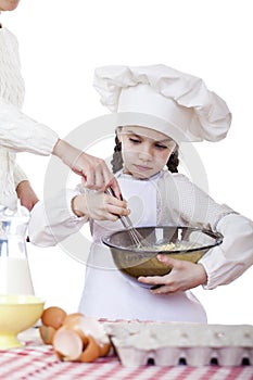 Little girl cook whips whisk eggs in a large plate