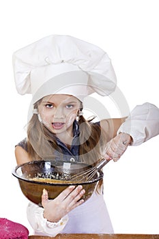 Little girl cook whips whisk eggs in a large plate photo