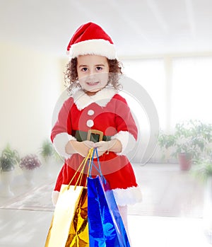 Little girl in costume of Santa Claus with colorful packages