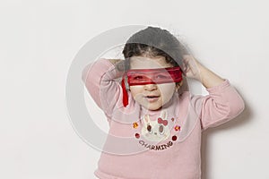 Little girl covered her eyes with a red ribbon super hero concept