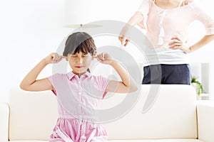 Little girl covering her ears while her mother angry