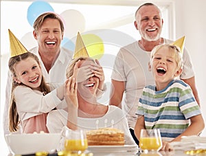 Little girl covering mothers eyes while celebrating her birthday or surprising her on Mothers day. Woman having a party