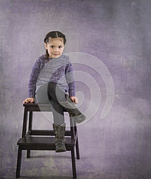 Little girl in cowboy boots and purple sweater