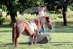 Little girl with cowboy hat and pony horse