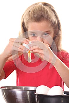 Little girl cracking egg to make cookies