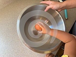 Little Girl Cracking Eggs to Add to Batter While Baking with Parents