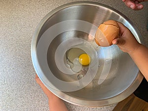 Little Girl Cracking Eggs to Add to Batter While Baking with Parents