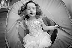 Little girl crawls inside toy tunnel at childrens holiday. Black white photo